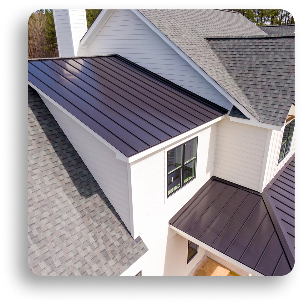 A modern house with white siding features both dark gray metal roofing and traditional gray asphalt shingles in a geometric layout, highlighting innovative North Texas residential and commercial roofing styles. Multiple roof sections and large windows are visible.