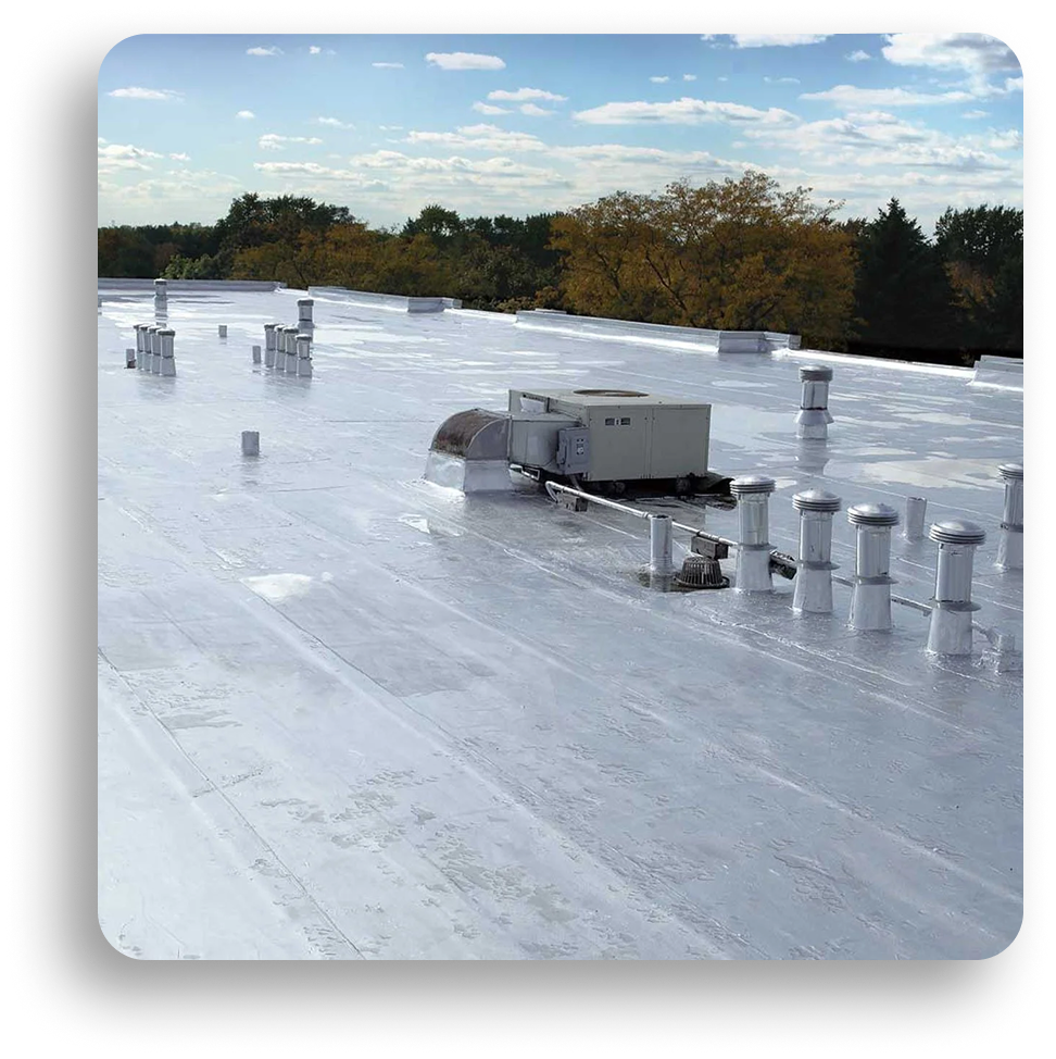 A flat commercial rooftop by American Patriot Roofing, covered with reflective white material, features multiple ventilation pipes, a large HVAC unit, and is surrounded by trees under a partly cloudy sky. Perfect for expert commercial roofing solutions.
